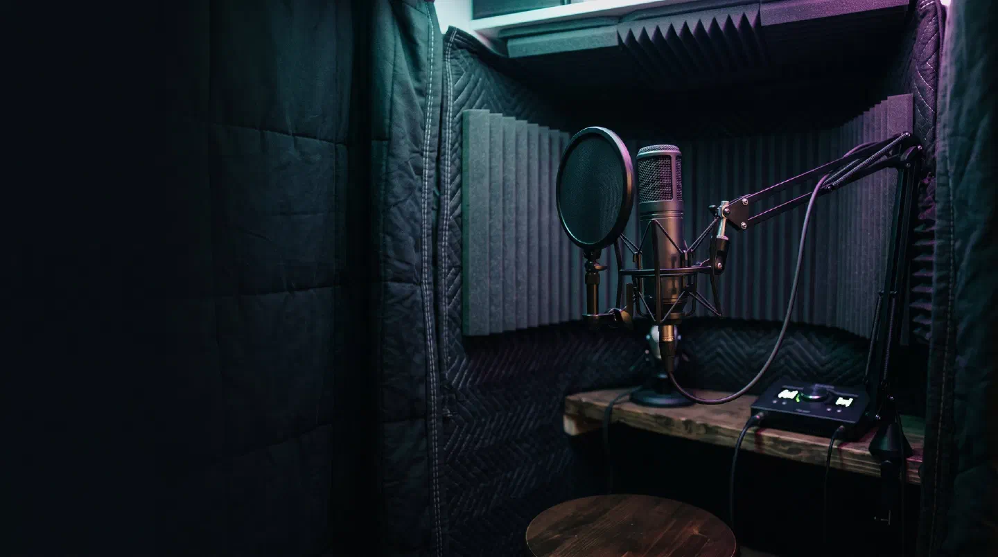 Cabina vocal casera con mantas y paneles de espuma y un micrófono con antipop