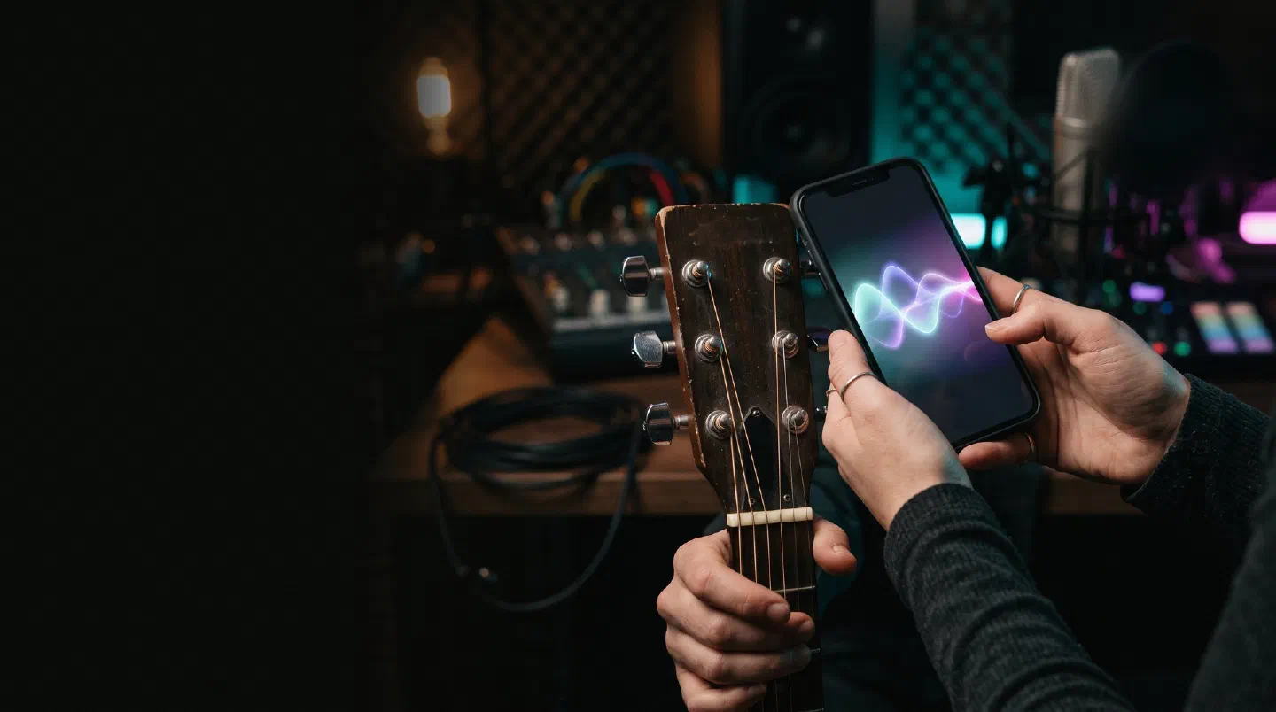 Manos con un móvil que muestra una forma de onda junto al clavijero de una guitarra