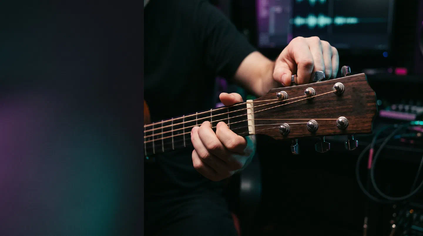 Manos girando las clavijas de una guitarra acústica
