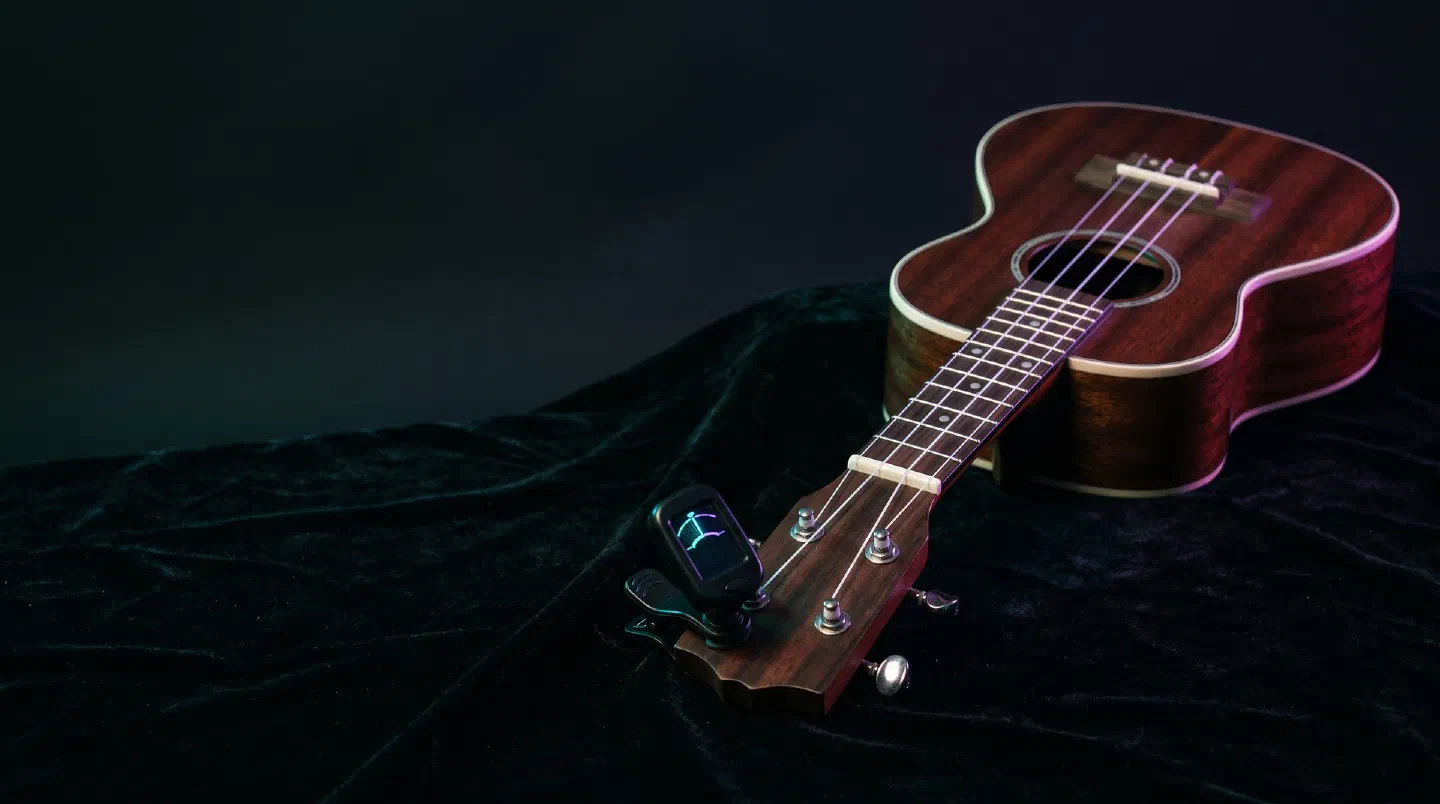 Ukelele de madera con un afinador de pinza en el clavijero